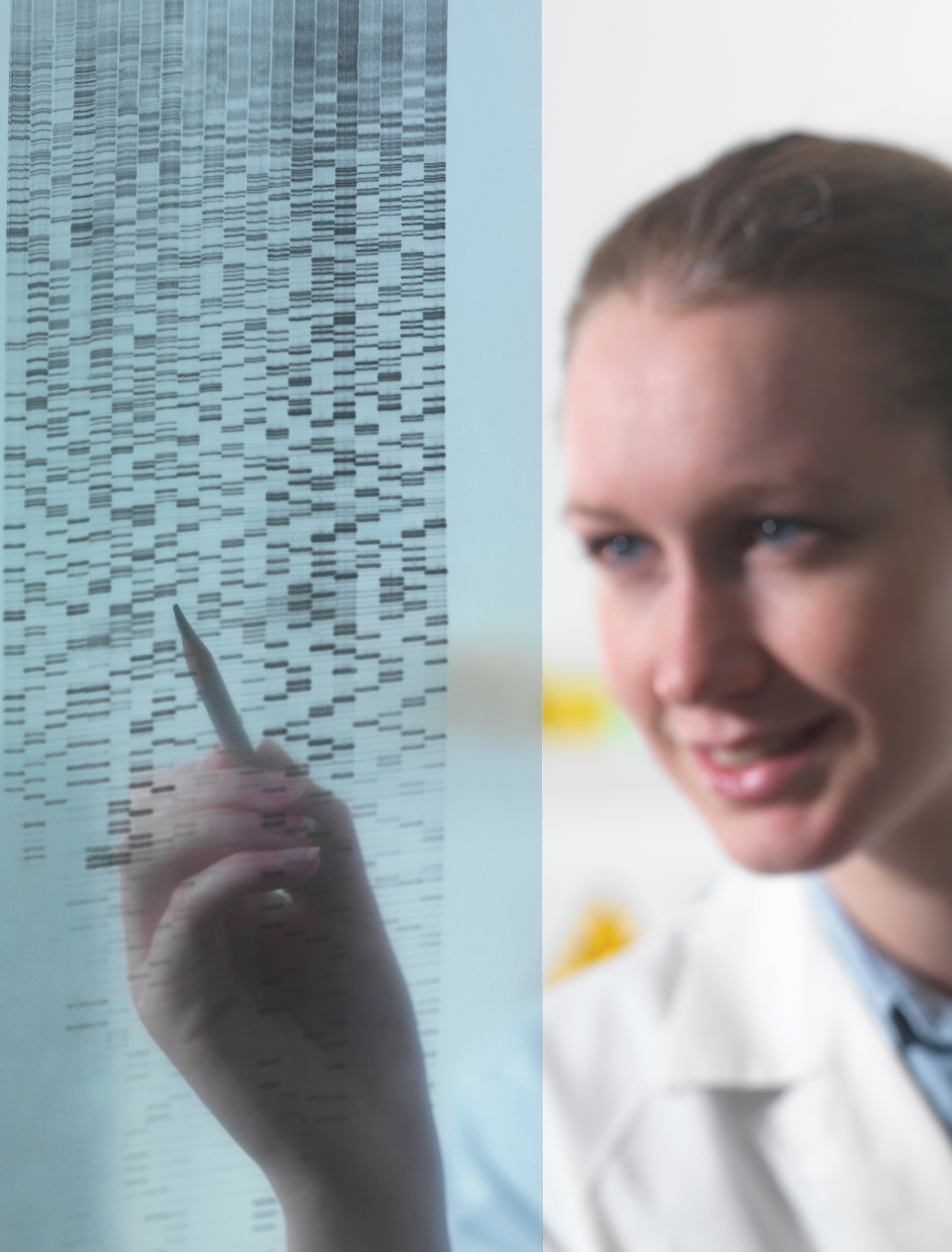 Female researcher examining DNA autoradiogram gel in laboratory.