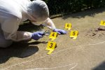 A crime scene technician places evidence markers at a crime scene