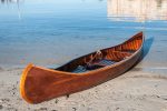 A wooden canoe sits on the water's edge