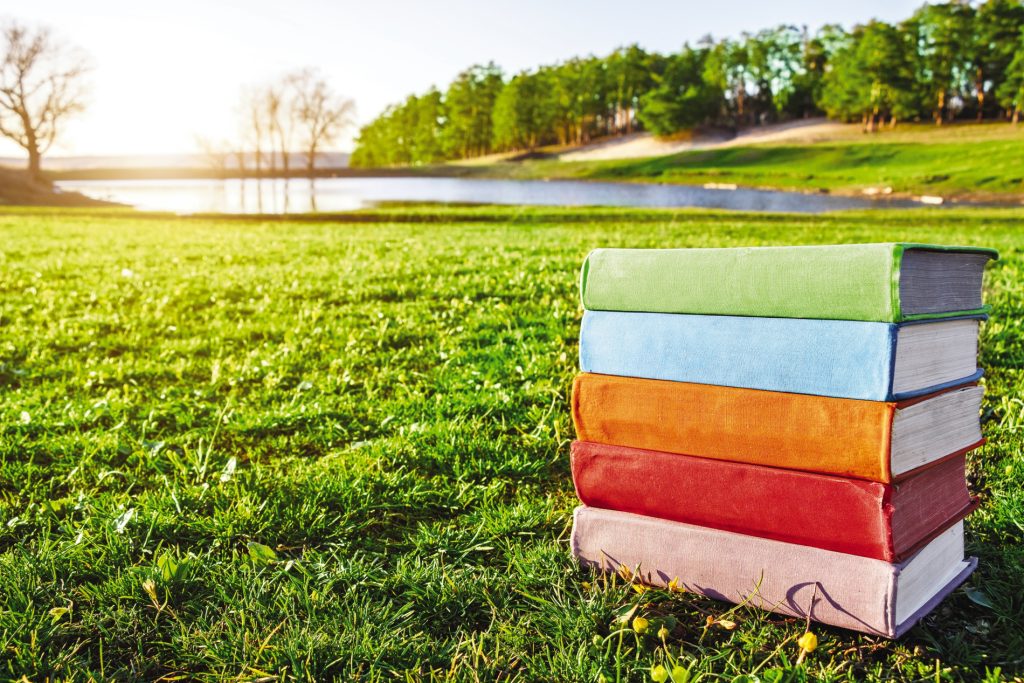 Colorful books are stacked up outdoors