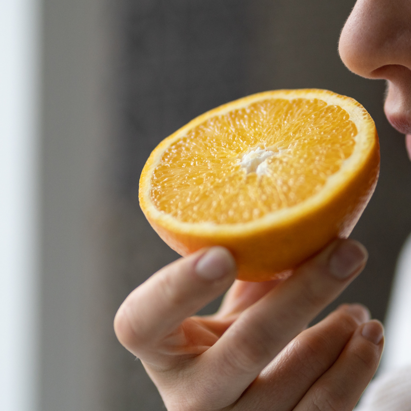 A woman smells a half orange.