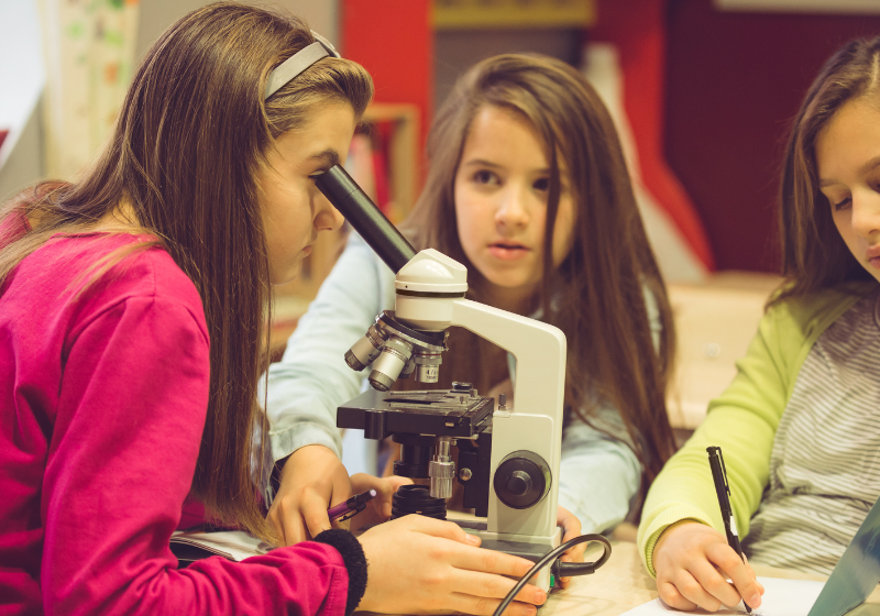 young students using a compound microscope in class