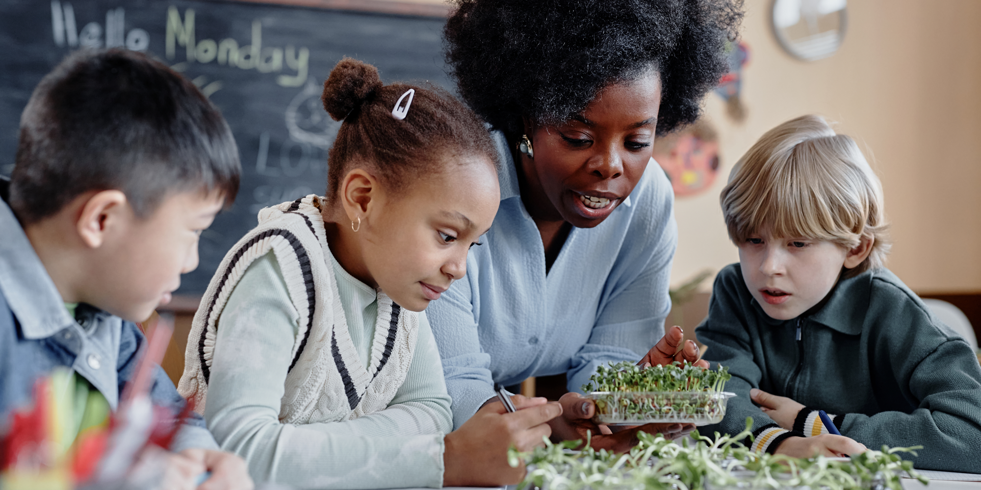 teacher showing students growing plants in classroom